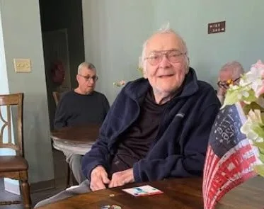 A resident smiling at the table in the shared common room