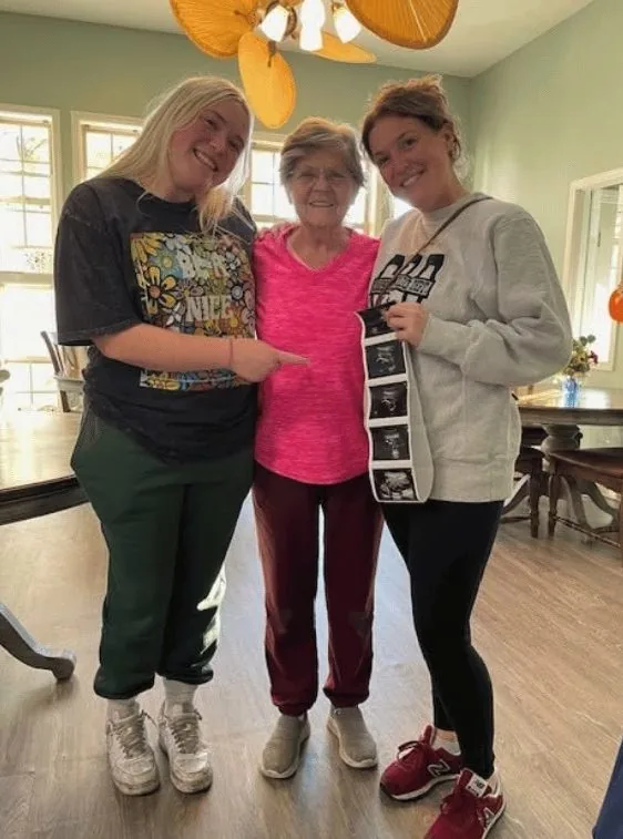 A resident with visiting family members sharing ultrasound photos of a new great-grandchild